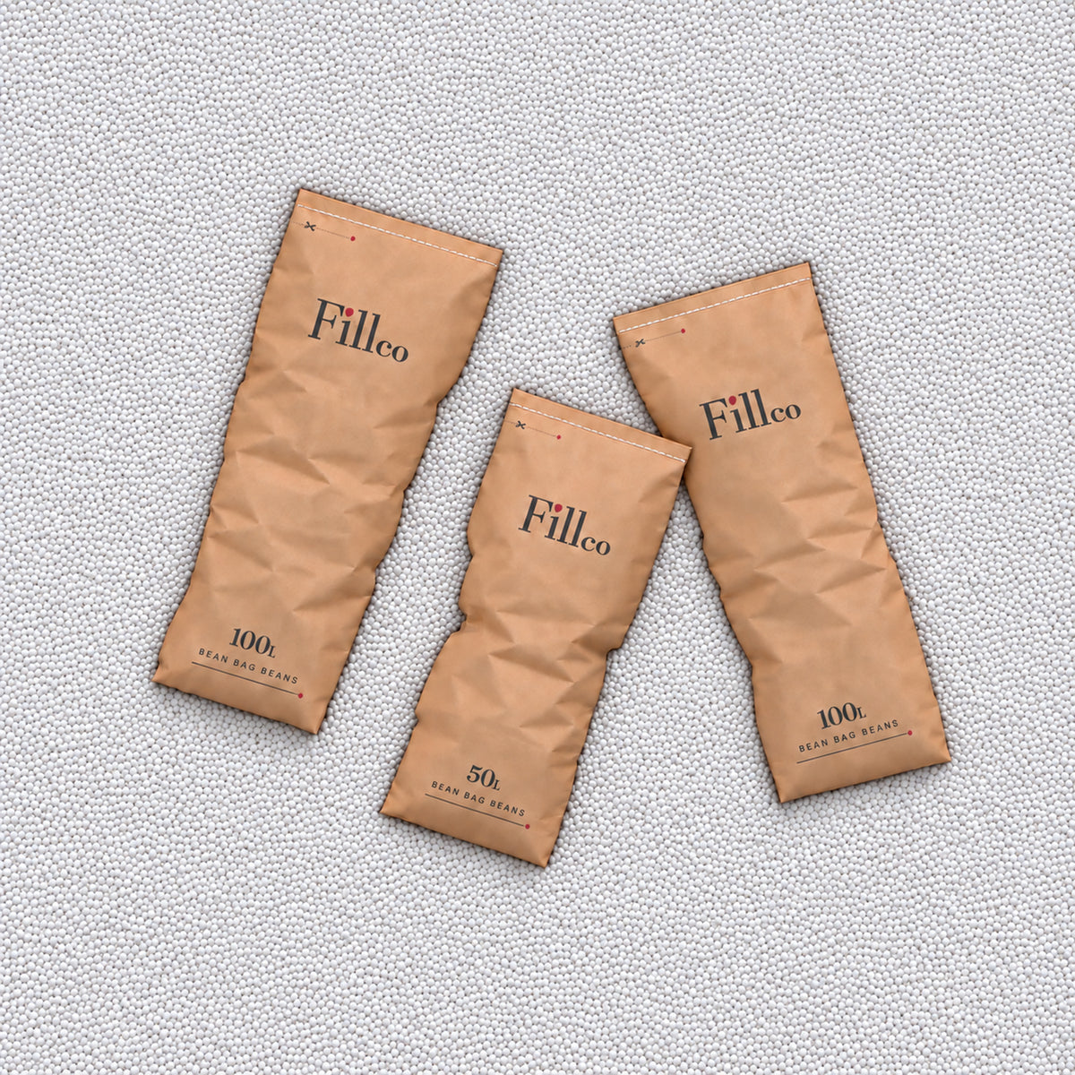 Three Fill Co paper bags lying on a bed of White beans