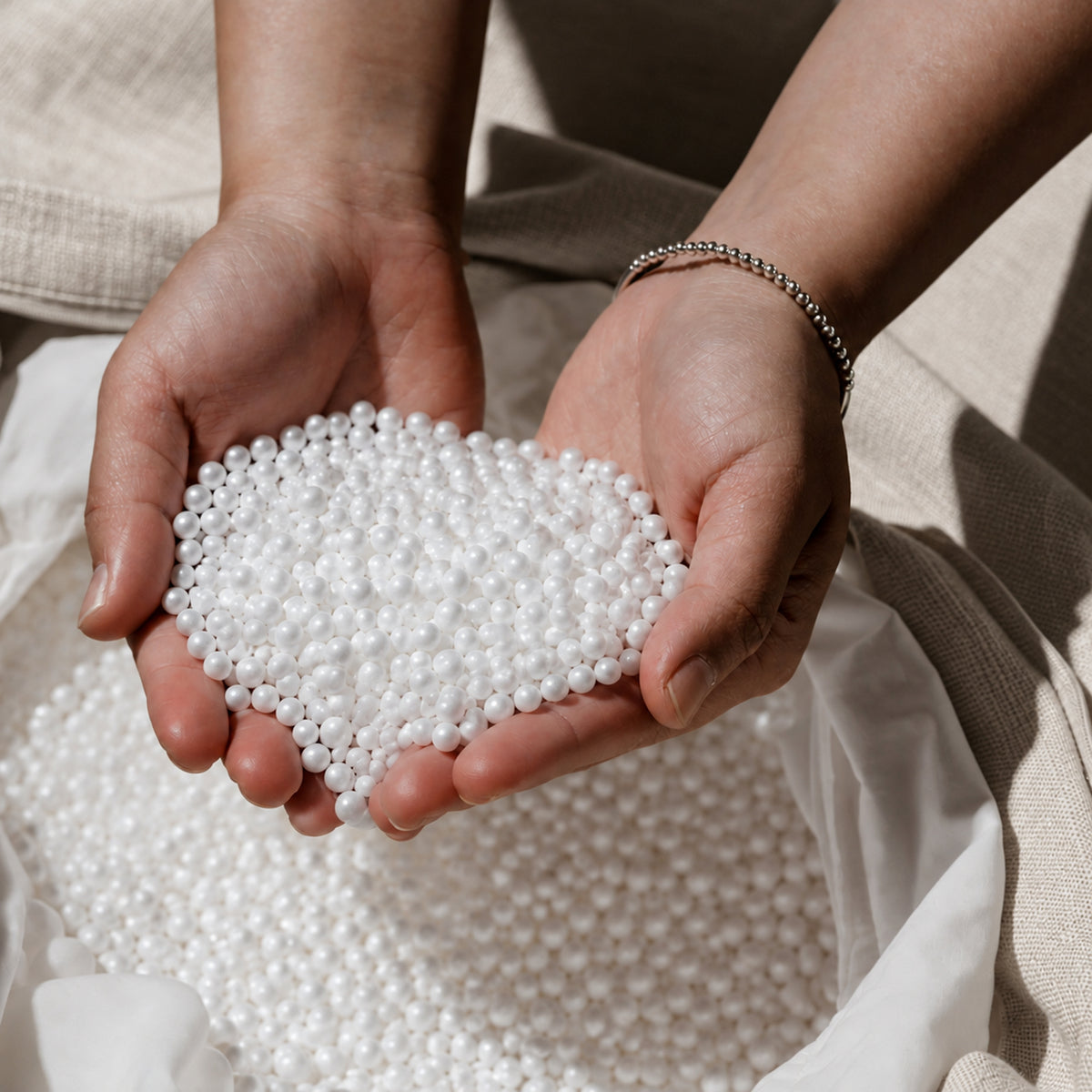 Two hands cupping Fill Co White bean bag beans over an oatmeal cover