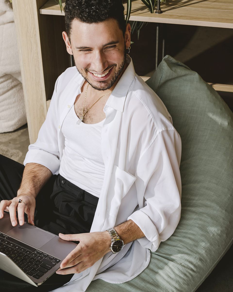 Man laughing on a green bean bag with a laptop