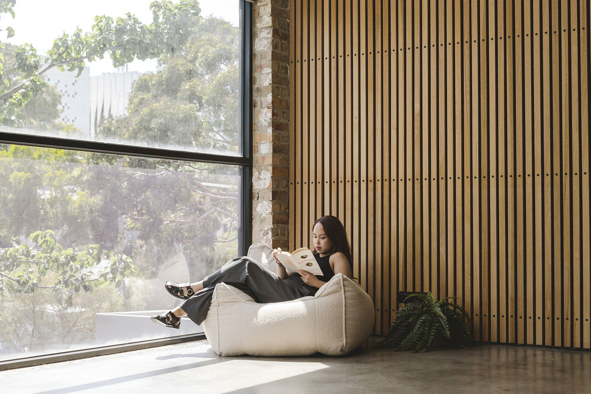 Woman reading on a bean bag beside a tall window